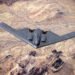A B-2 Spirit stealth bomber flying with GBU-57 MOP explosions detonating across a desert landscape below.