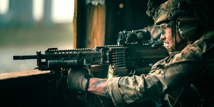 A U.S. Army 75th Ranger armed with a KAC LAMG having an ELCAN Specter prism sight at the upper receiver's picatinny rail.